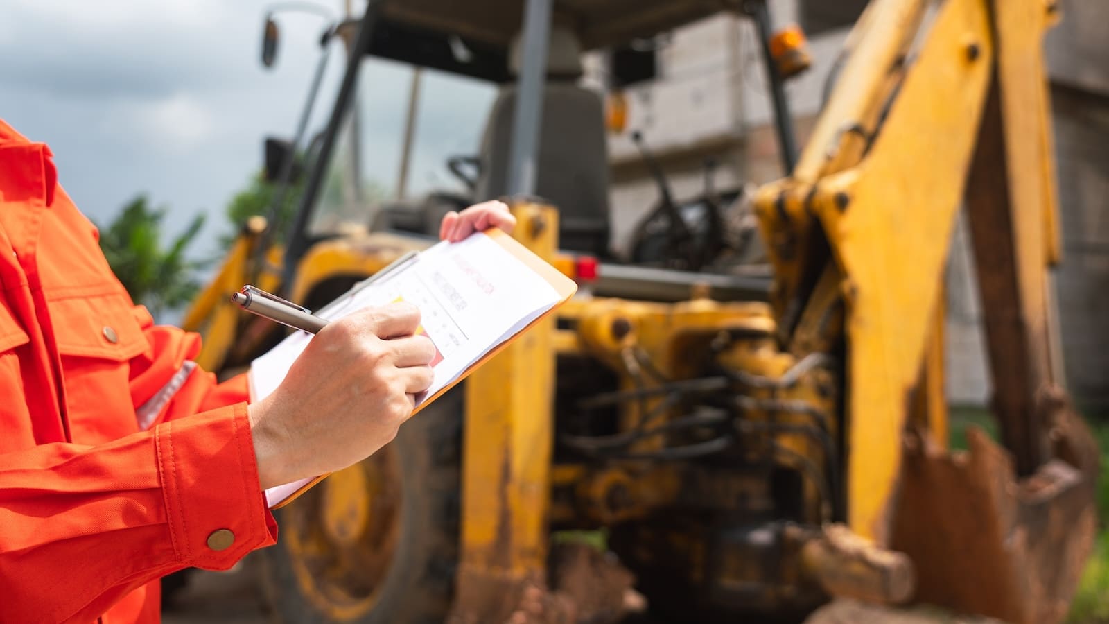 A mechanic inspecting the undercarriage and tracks of an excavator